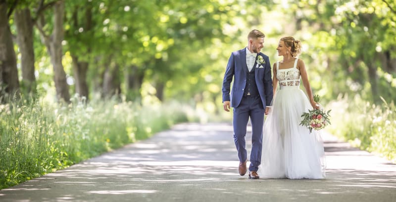 Ženích a nevesta kráčajú alejou, moderná svadobná fotografia